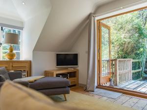 a living room with a tv and a large window at The Manor Coach House in Chilham
