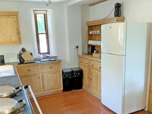 a kitchen with a white refrigerator and wooden cabinets at North Barn in Tolpuddle