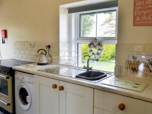 un bancone della cucina con lavandino e finestra di Sheilas Cottage a Christon Bank