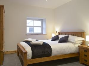 um quarto com uma cama com lençóis brancos e uma janela em Stambar em Llanglydwen