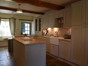 a kitchen with white cabinets and a counter top at Inglenook Cottage in Grassington