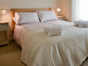 a large white bed with two pillows on it at Inglenook Cottage in Grassington