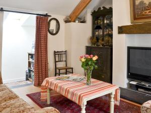 a living room with a table with a vase of flowers on it at Pant Y Mel in Brynteg