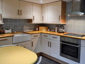a kitchen with white cabinets and a yellow table at Eirianfa in Penmachno