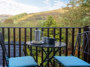 a table with two cups and two chairs on a balcony at Eirianfa in Penmachno