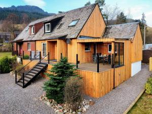 ein großes Holzhaus mit einer Veranda und einer Terrasse in der Unterkunft Ratagan Lodge in Kintail