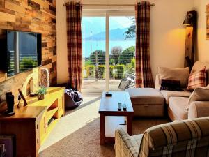 a living room with a couch and a tv at Ratagan Lodge in Kintail