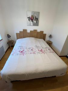 een bed met een witte sprei met roze bloemen erop bij Les mimosas in La Bresse