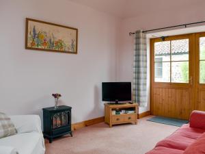 a living room with a couch and a tv at The Cottage At Cauldcoats in Linlithgow