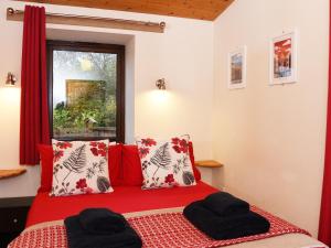 a bedroom with a red bed with pillows and a window at Ash Lodge - Hw7442 in Nantmel