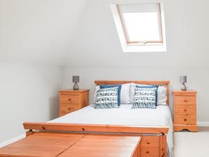 um quarto com uma cama de madeira, 2 cómodas e uma janela em Summer Hill em Kilgetty