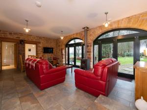 a living room with two red chairs and a tv at Cart Shed in Mauchline