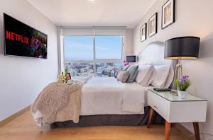 Schlafzimmer mit einem großen weißen Bett und einem Fenster in der Unterkunft Skyliving Towers Apartments - Perú in Lima