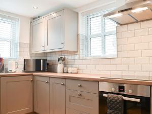 a kitchen with white cabinets and a microwave at The Old Chapel in Ashover