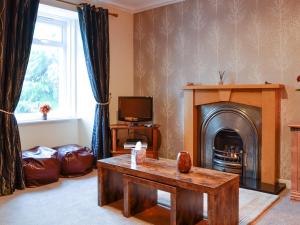 sala de estar con mesa y chimenea en Larch Cottage, en Blairgowrie