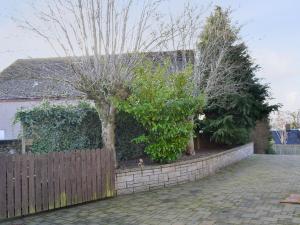 a house with a fence with a tree and bushes at Larch Cottage in Blairgowrie