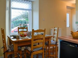 eine Küche mit einem Holztisch und Stühlen sowie einem Fenster in der Unterkunft Larch Cottage in Blairgowrie