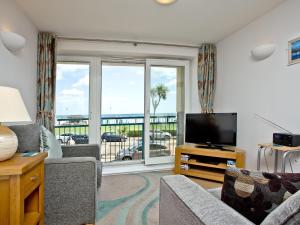 a living room with a television and a view of the ocean at 16 Belvedere Court in Paignton
