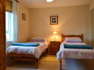a bedroom with two beds and a lamp and a window at Brae Lodge in Cullen