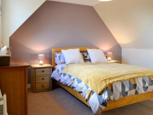Larch Cottage في بليرغوري: غرفة نوم بسرير ومكتب فيه مصباحين