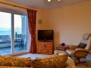 a living room with a television and a balcony at Brae Lodge in Cullen