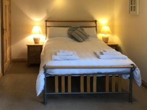 um quarto com uma cama grande e toalhas em Honeysuckle Cottage em Oasby