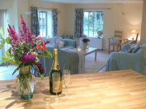a bottle of champagne and two glasses on a table at Honeysuckle Cottage in Oasby