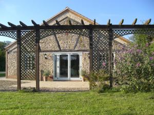 a stone house with a pergola in a yard at Honeysuckle Cottage in Oasby