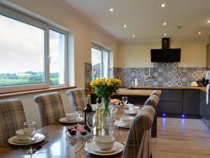 comedor con mesa con sillas y cocina en Marlais View en Llansadwrn