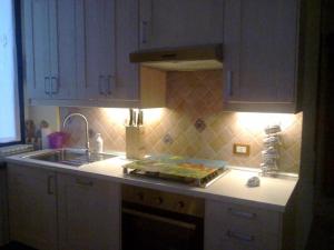 uma cozinha com armários brancos, um lavatório e um balcão em i tulipani em Miagliano