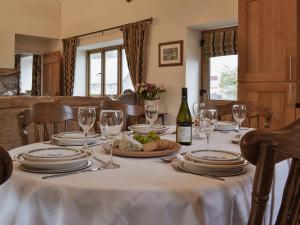 a dining room table with a white table cloth and a bottle of wine at The Old Byre in Rhossili