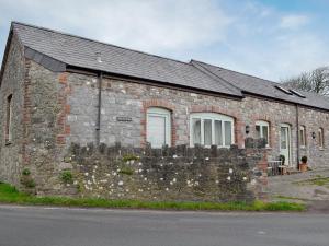 a brick building with a stone wall next to a street at The Old Byre in Rhossili