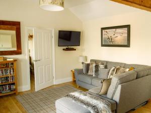 a living room with a couch and a tv at Gannet Lodge - Uk30977 in Bempton