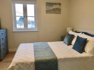 a bedroom with a bed with blue pillows and a window at Curlew in Brightlingsea