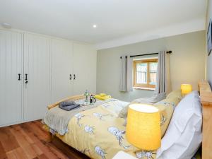 ein Schlafzimmer mit einem großen Bett und einer gelben Lampe in der Unterkunft Stackyard Cottage in Felmingham