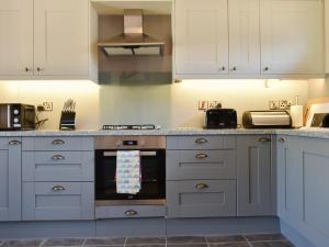 a kitchen with white cabinets and an oven at Cider Press Barn - Uk12379 in Lydney