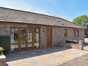 a brick house with wooden doors and a patio at Cider Press Barn - Uk12379 in Lydney