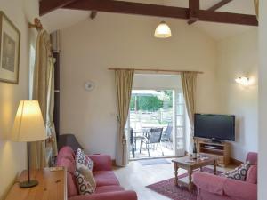 a living room with a pink couch and a tv at Cothi Cottage in Llanfynydd