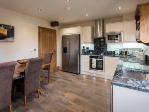 uma cozinha com uma mesa e cadeiras e um frigorífico em Sycamore Barn - Uk33353 em Buttershaw
