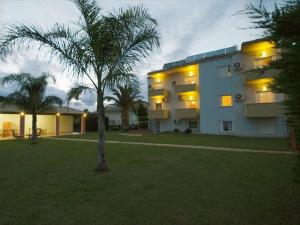 a large building with a palm tree in front of it at Voula Apartments in Mytikas