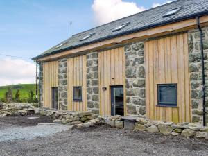 ein Gebäude aus Stein und Holz mit einer Steinmauer in der Unterkunft Dutch Barn One - Uk12872 in Brynkir