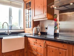 a kitchen with wooden cabinets and a sink at Trondra House in Ferryside