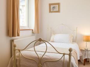 1 dormitorio con cama blanca y ventana en Trondra House, en Ferryside