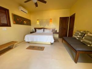 um quarto com uma cama branca e um sofá em Siete Piedras Beachfront Village em Troncones