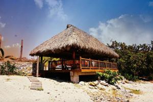 a hut with a deck on the beach at Siete Piedras Beachfront Village in Troncones