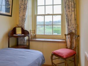 Delabole的住宿－道恩房屋鄉村別墅，一间卧室设有一张床、一个窗口和一把椅子