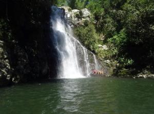 a group of people in the water in front of a waterfall at LE VÉTIVER Cosy Appartement proche Aéroport in Sainte-Marie