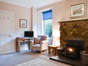 sala de estar con chimenea de piedra y silla en Ingleside, en Whiting Bay