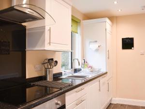 una cocina con armarios blancos y encimeras negras en Ingleside, en Whiting Bay