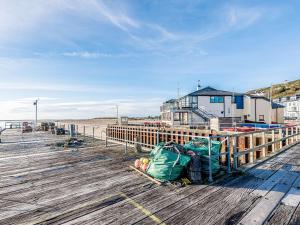 a wooden boardwalk with a building on the beach at Sunny Shores - Uk32245 in Aberdyfi